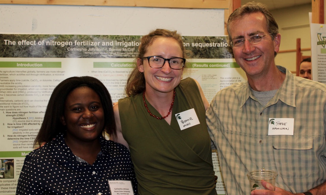 Three people standing in front of a research poster smiling.